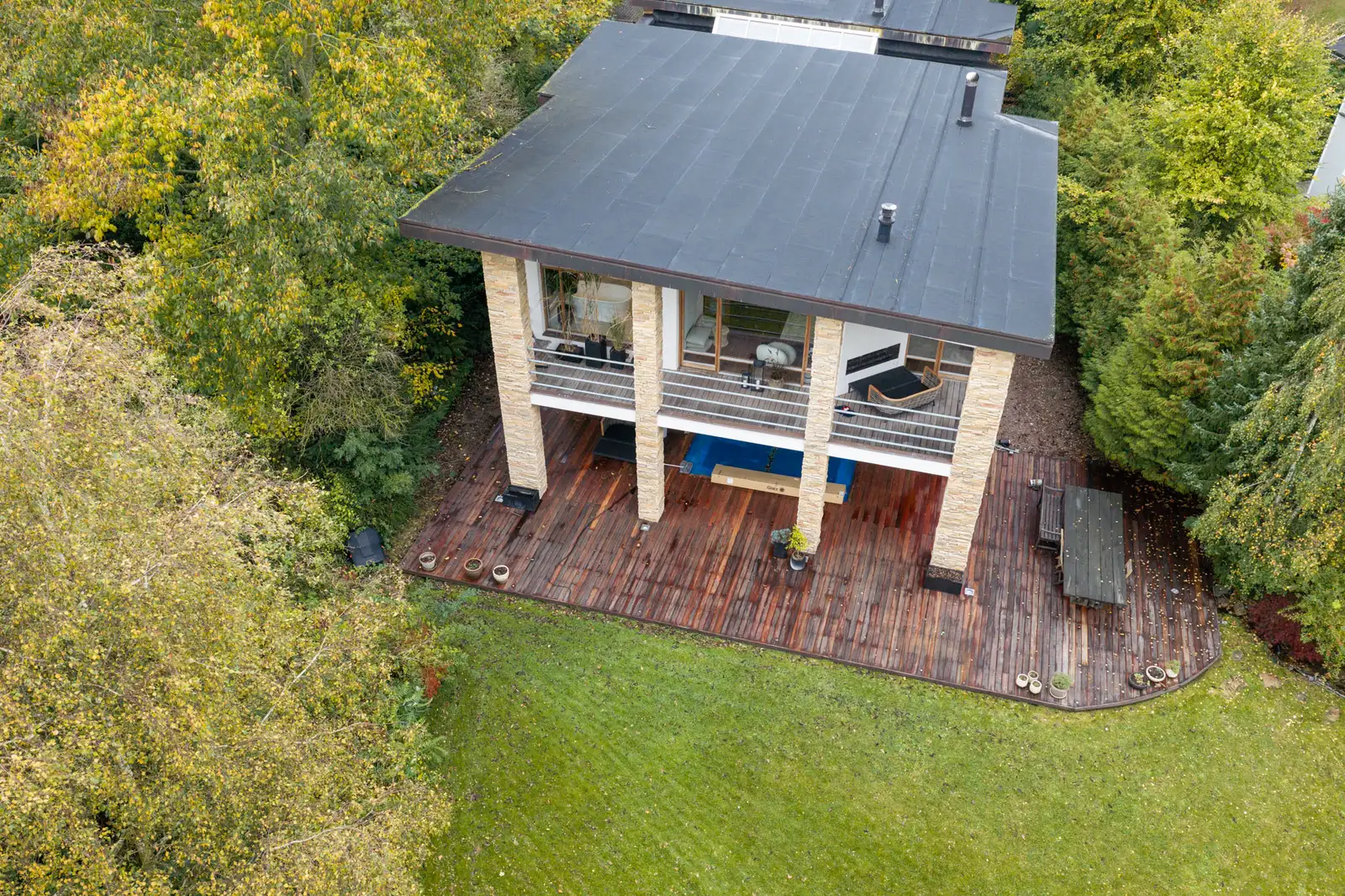 Villa med tagterrasse og træterrasse ud mod haven, set fra drone